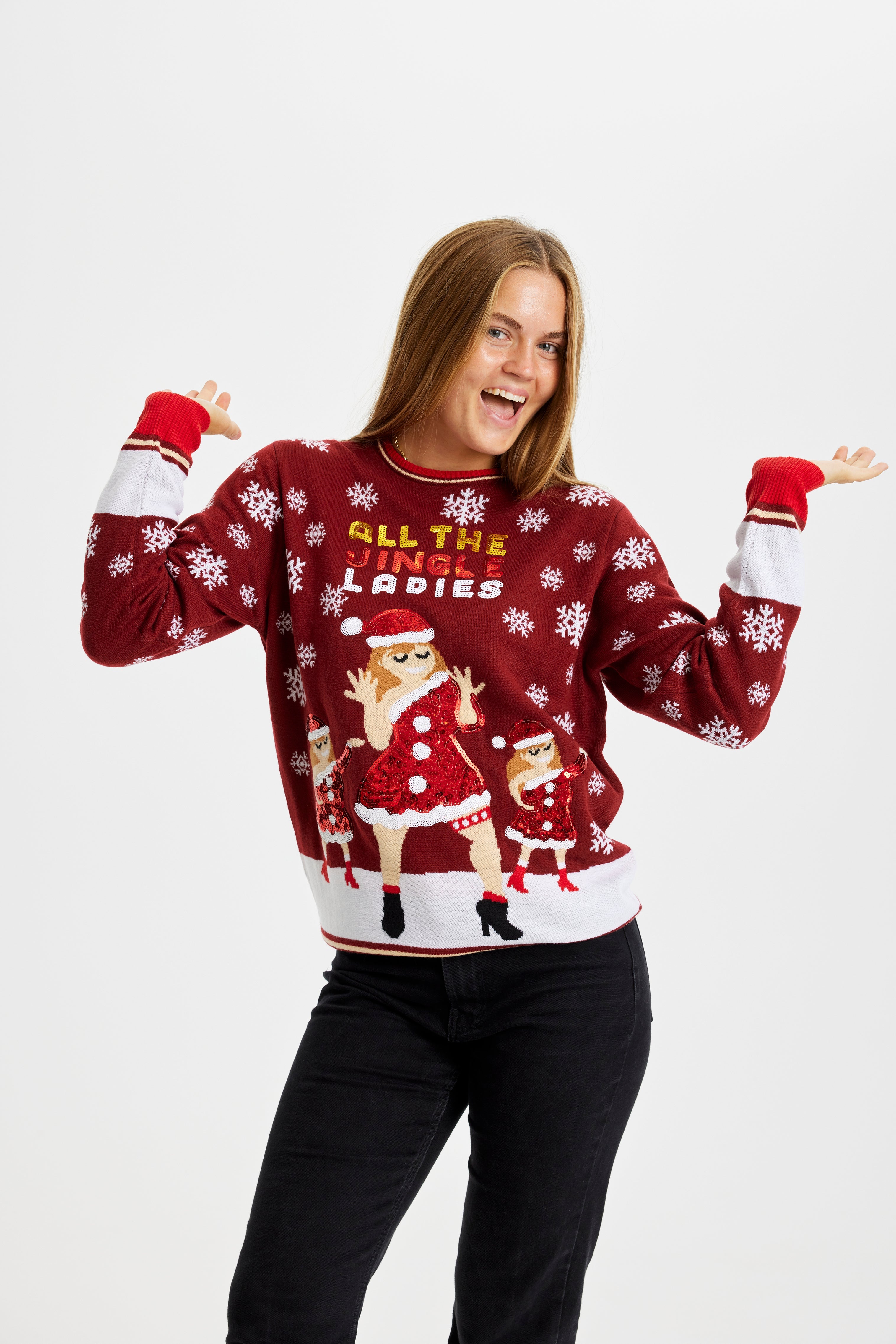 En meget glad dame står med hænderne i vejret og er iført en julesweater med citatet